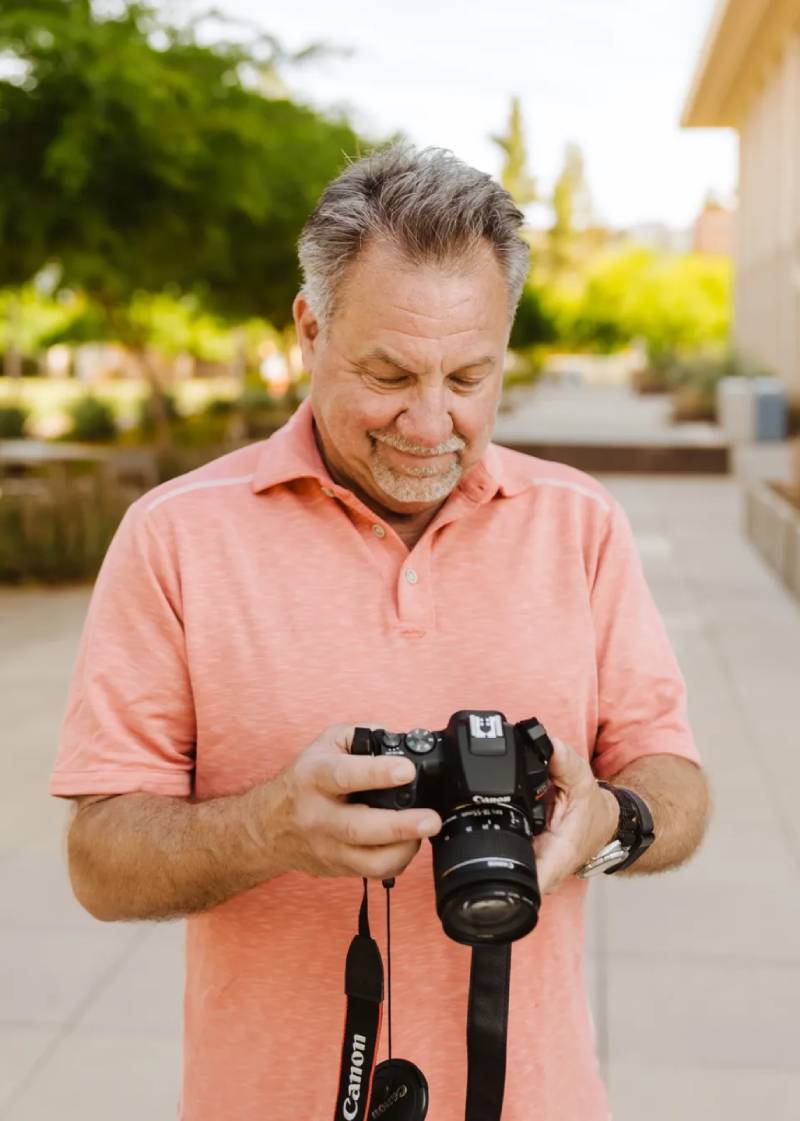 A man holding a camera and looking at the screen.